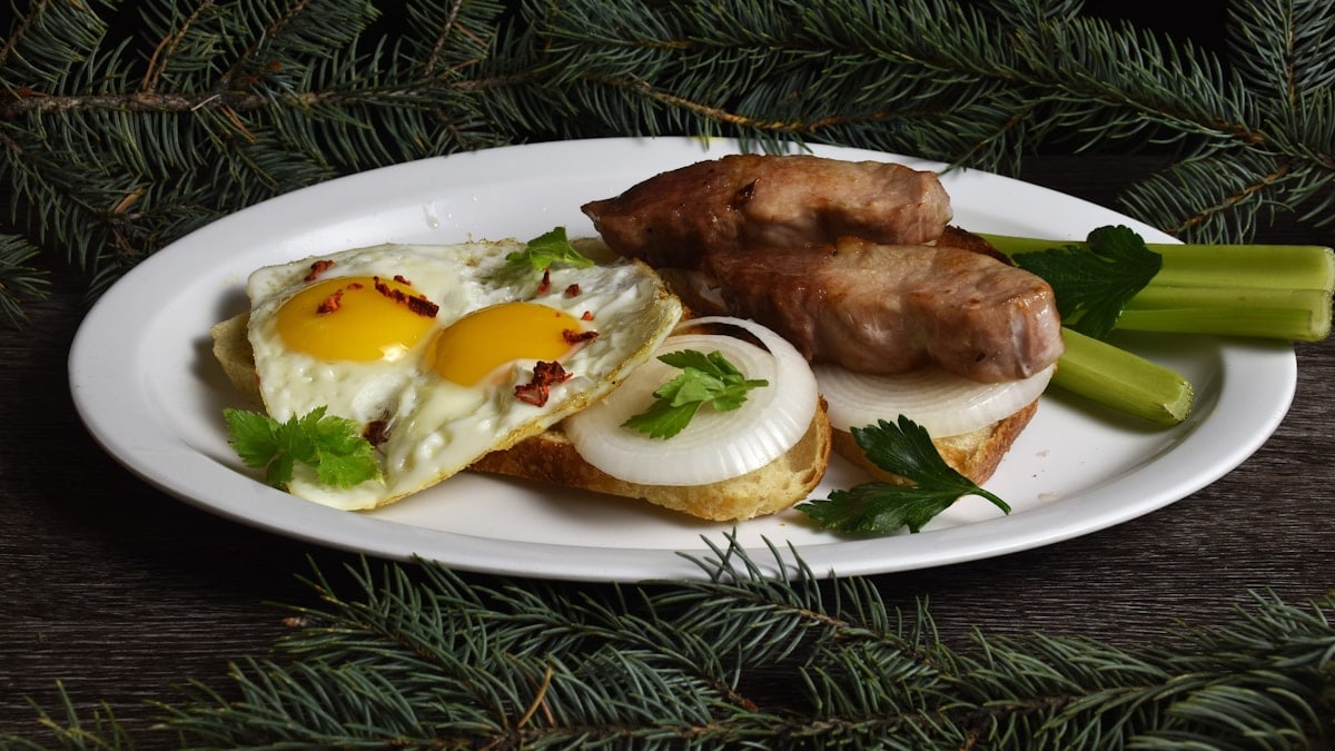 A white plate topped with meat and eggs